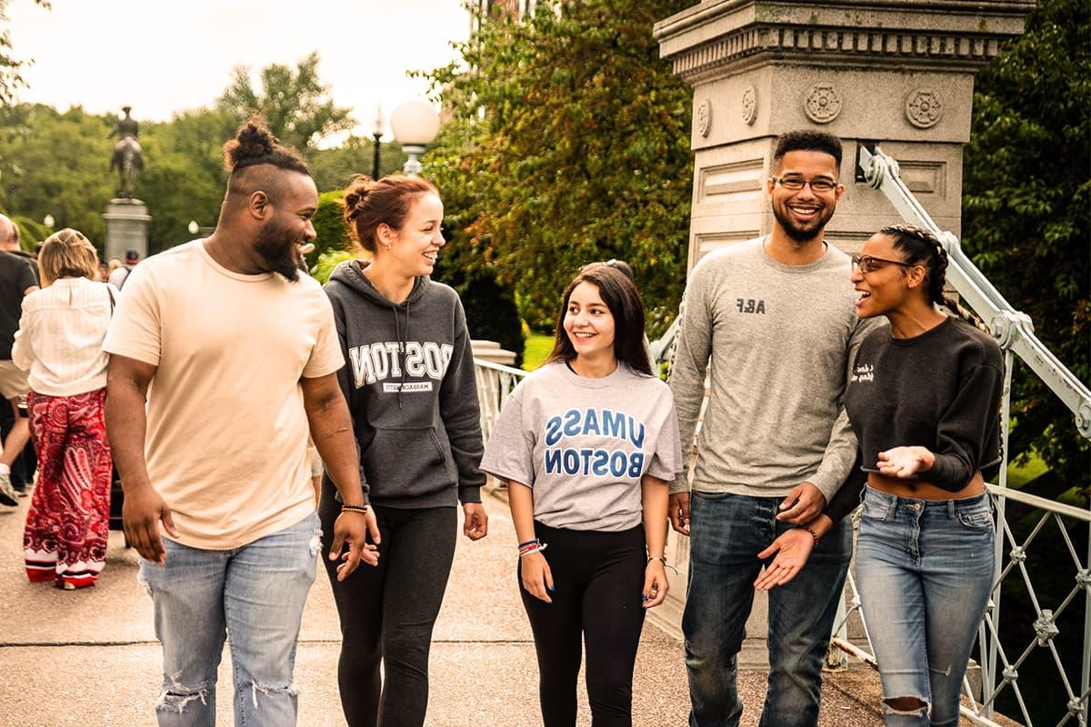 4名穿着波士顿大学服装的学生走过波士顿公共花园的大门.